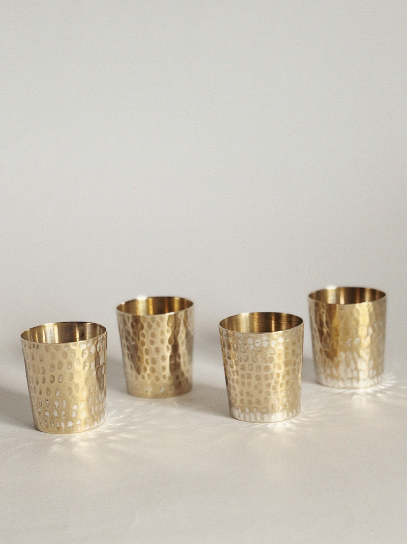 Four Huerto silver plated cups are arranged in a row on a light, neutral background, casting soft shadows and gentle reflections across the surface.