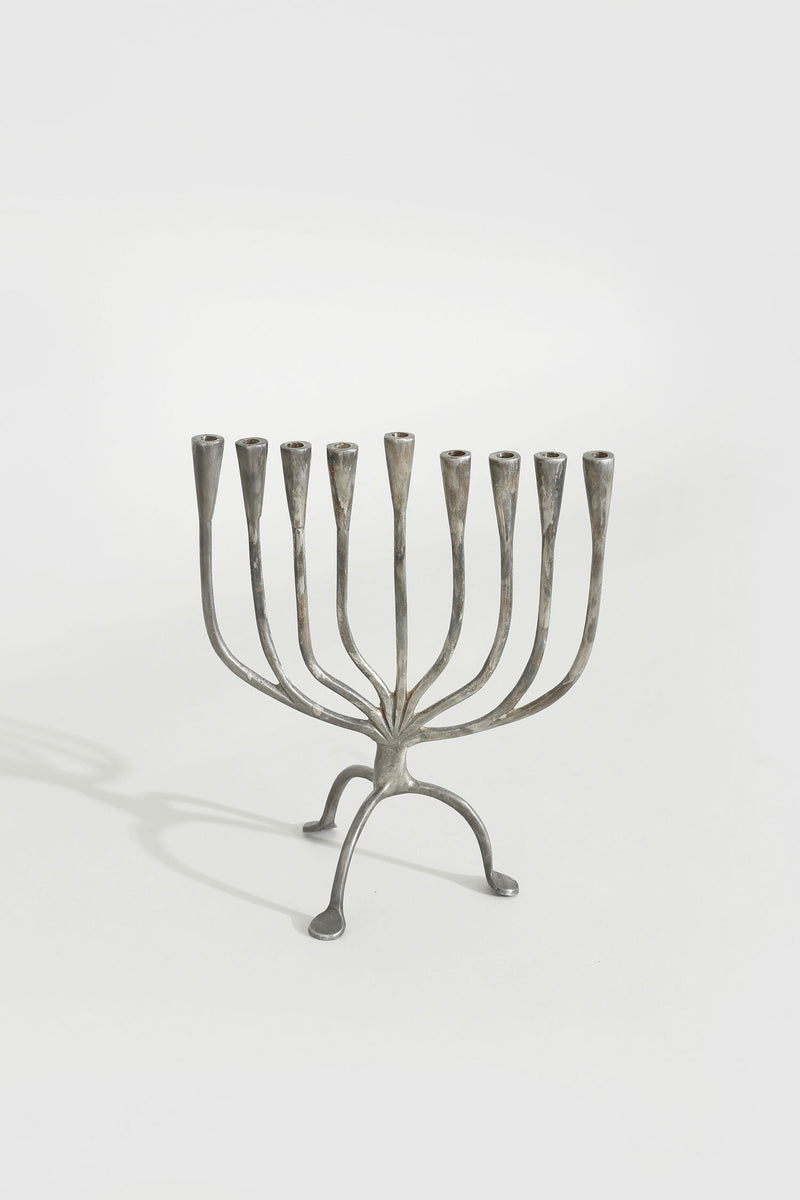 Brutalist metal menorah with nine curved candle holders on tripod base