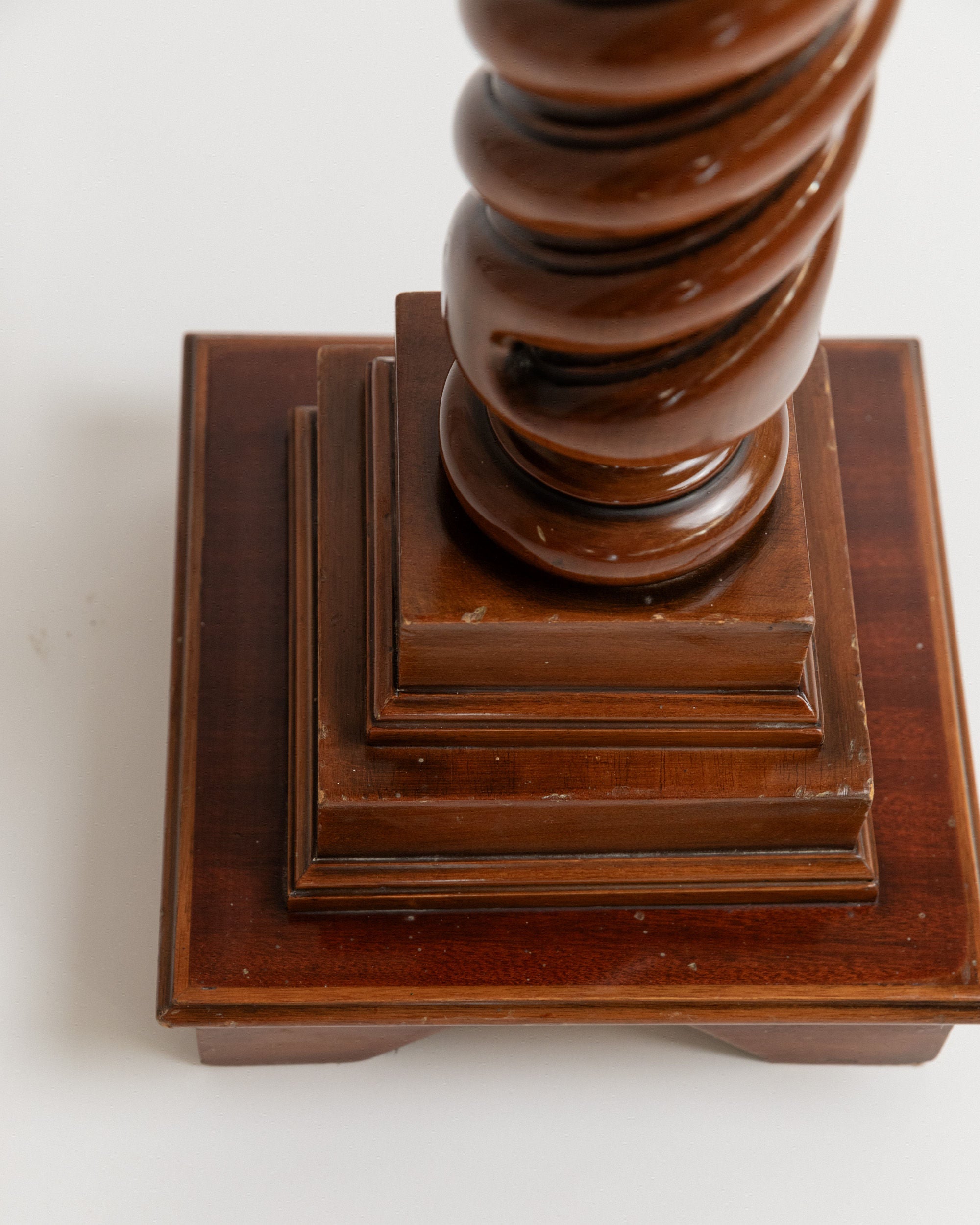 Close-up of a polished Bottega Jacobs 1960s Italian wooden stand, featuring a spiral pedestal. The base has stacked square layers of dark wood resembling a vintage flower stand, creating an elegant and sturdy support with a smooth, glossy surface.