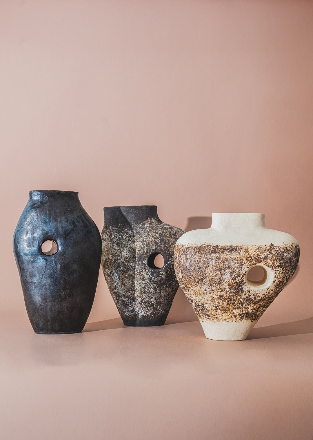 The Silhouette Vase 06 from Siham Djebbar Ceramics’ Tunnel Series features a handcrafted stoneware form with abstract contours and circular holes, creating a striking sculptural display against a soft beige backdrop.
