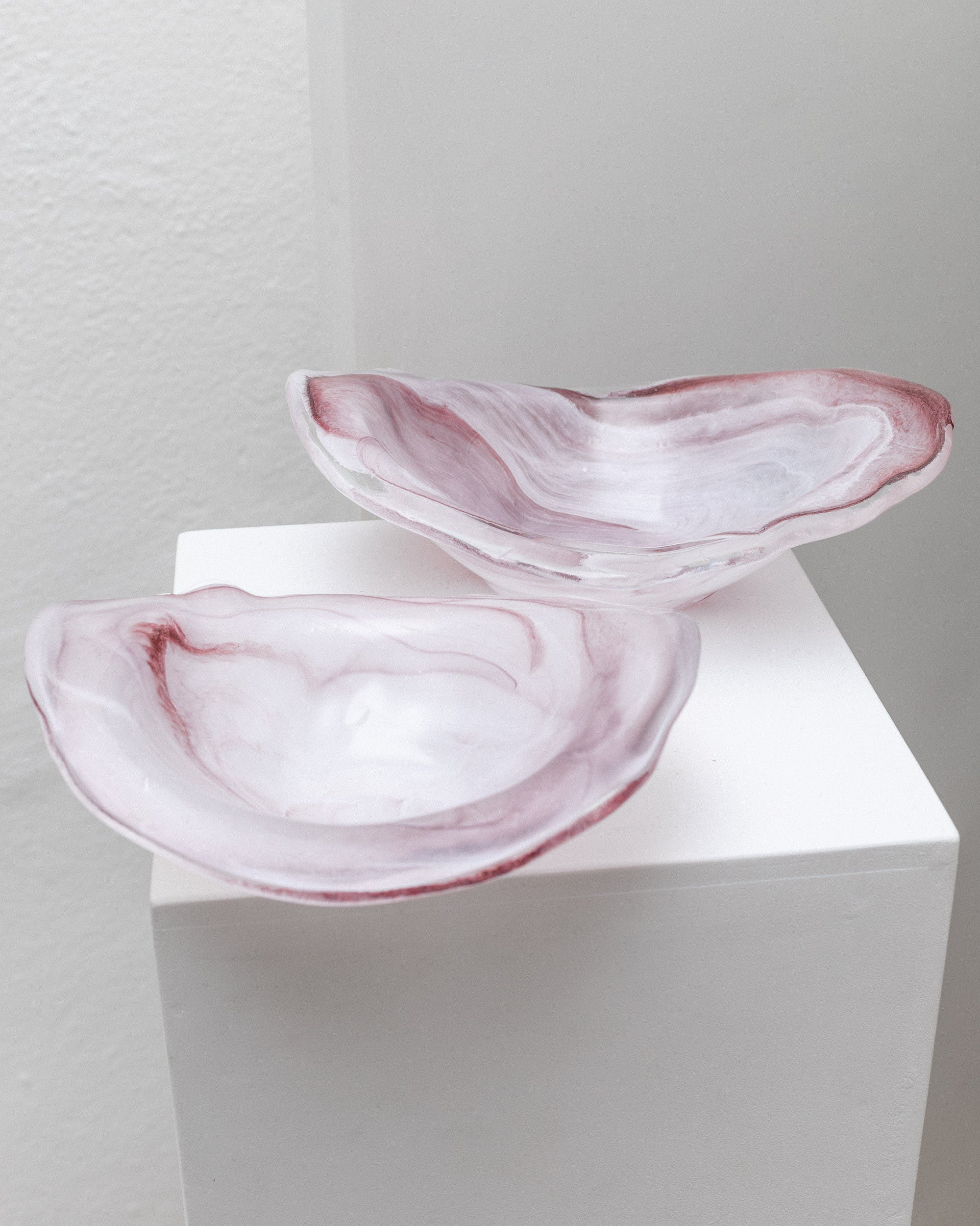 Two Murano Glass Bowls by Bottega Jacobs, Italy 1970s, with marbled pink and white patterns sit on a white pedestal against a plain background.