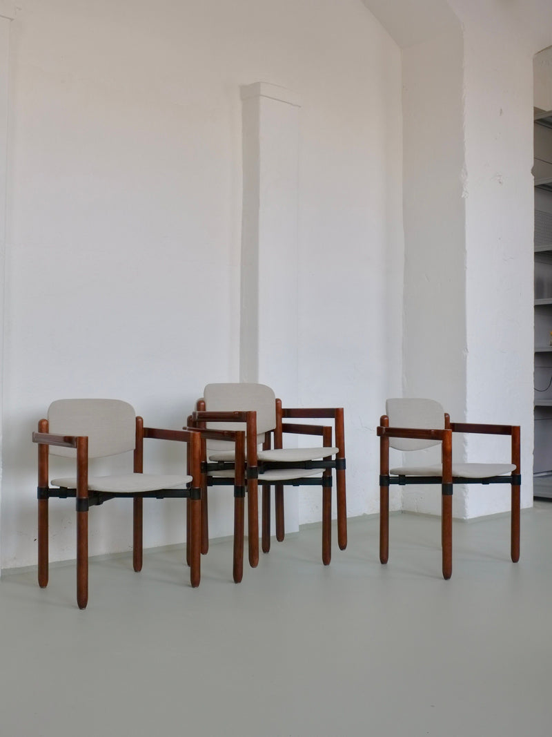 A minimalist room showcases a set of three Fröscher Sitform armchairs by Veter Vintage, with light beige upholstery and black metal connecting rods. These wooden pieces, echoing 1970s design, combine sleek lines and modern artistry against a white wall.