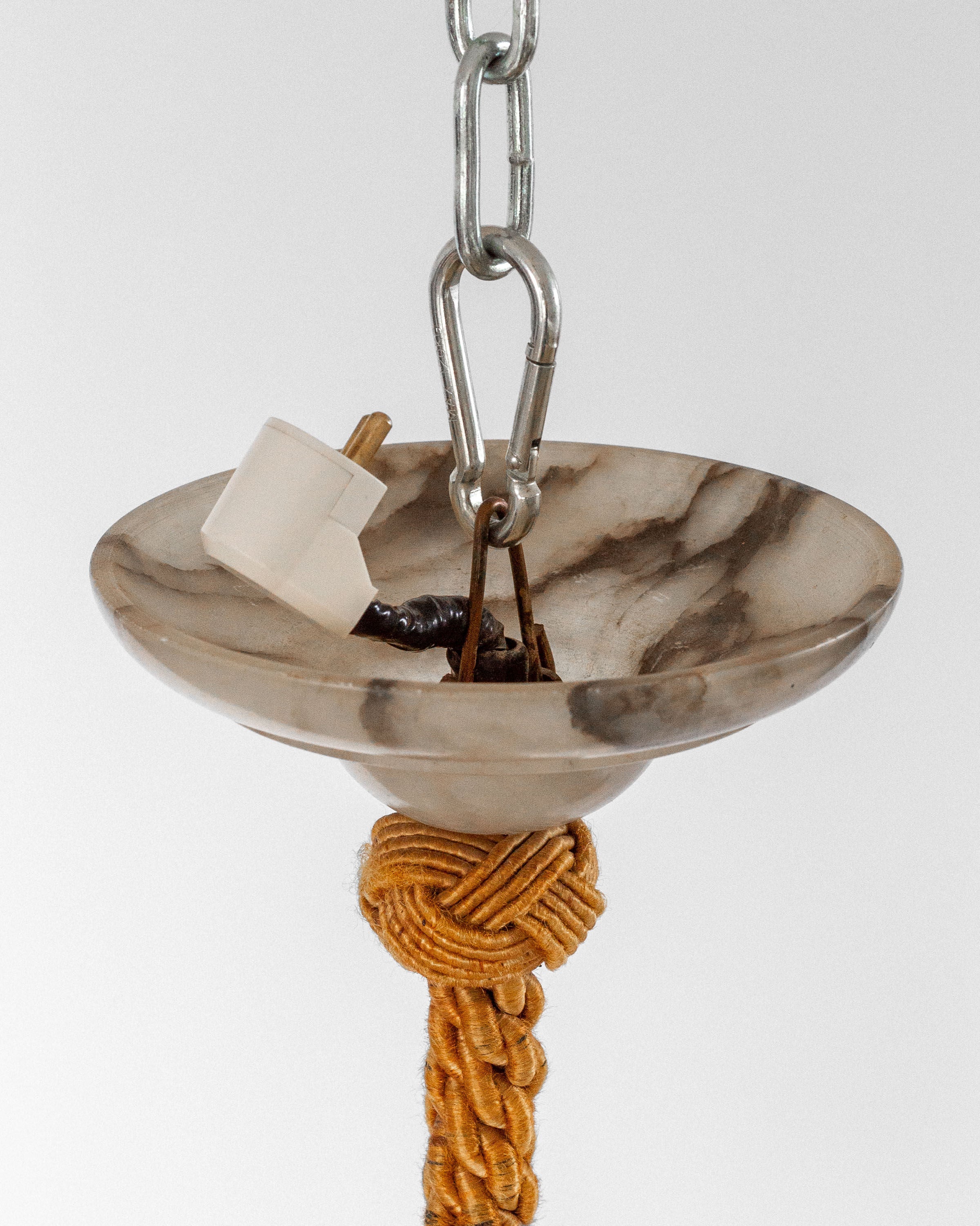 The Spigel Art Deco Alabaster Pendant Chandelier features a marbled bowl and metal chain for timeless charm. A beige rope beneath the bowl conceals wiring, while a white plug is centered. It evokes classic Swedish Grace lighting against a plain, light background.