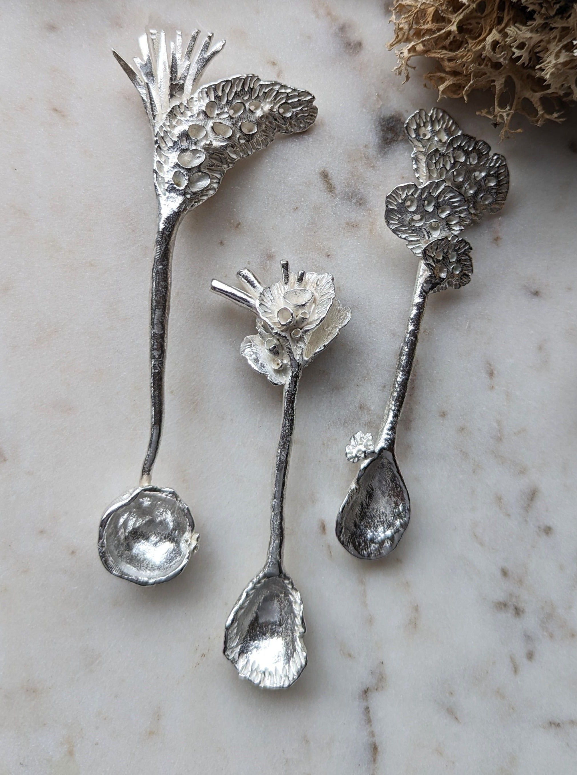 A woman's hand holding a unique lichen spoon made of natural materials