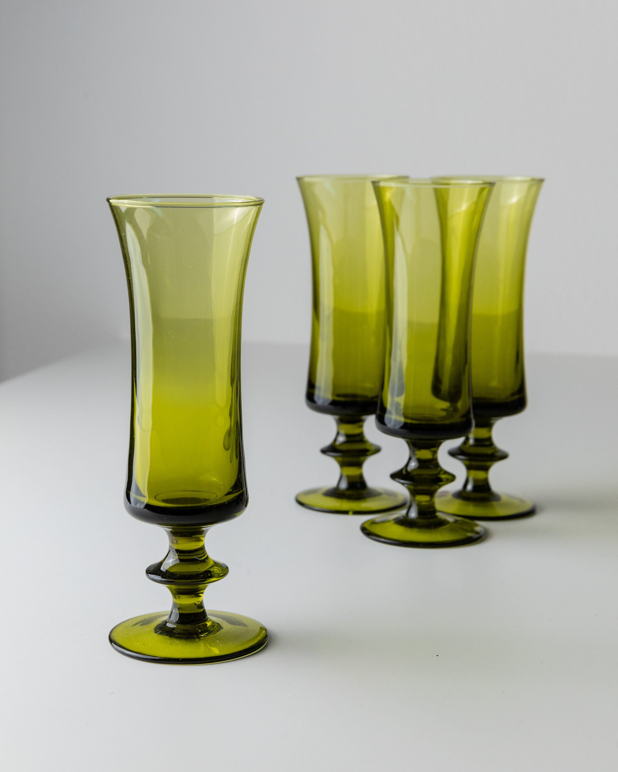 The 4 Murano Glasses in Green 70s by Bottega Jacobs radiate retro chic with their translucent fluted design, wide bases, and vintage artistry, elegantly positioned on a white surface against a light gray background.