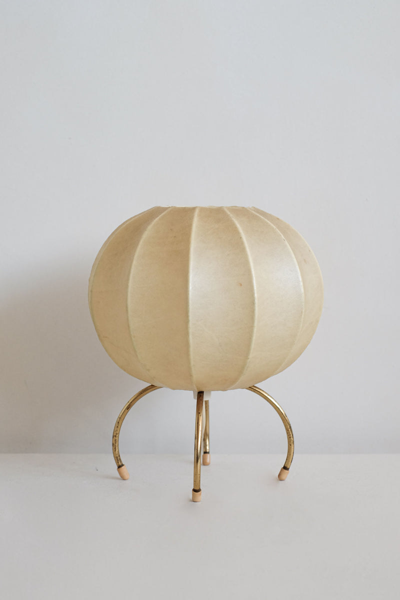 Cocoon table lamp with pleated cream shade on brass tripod legs