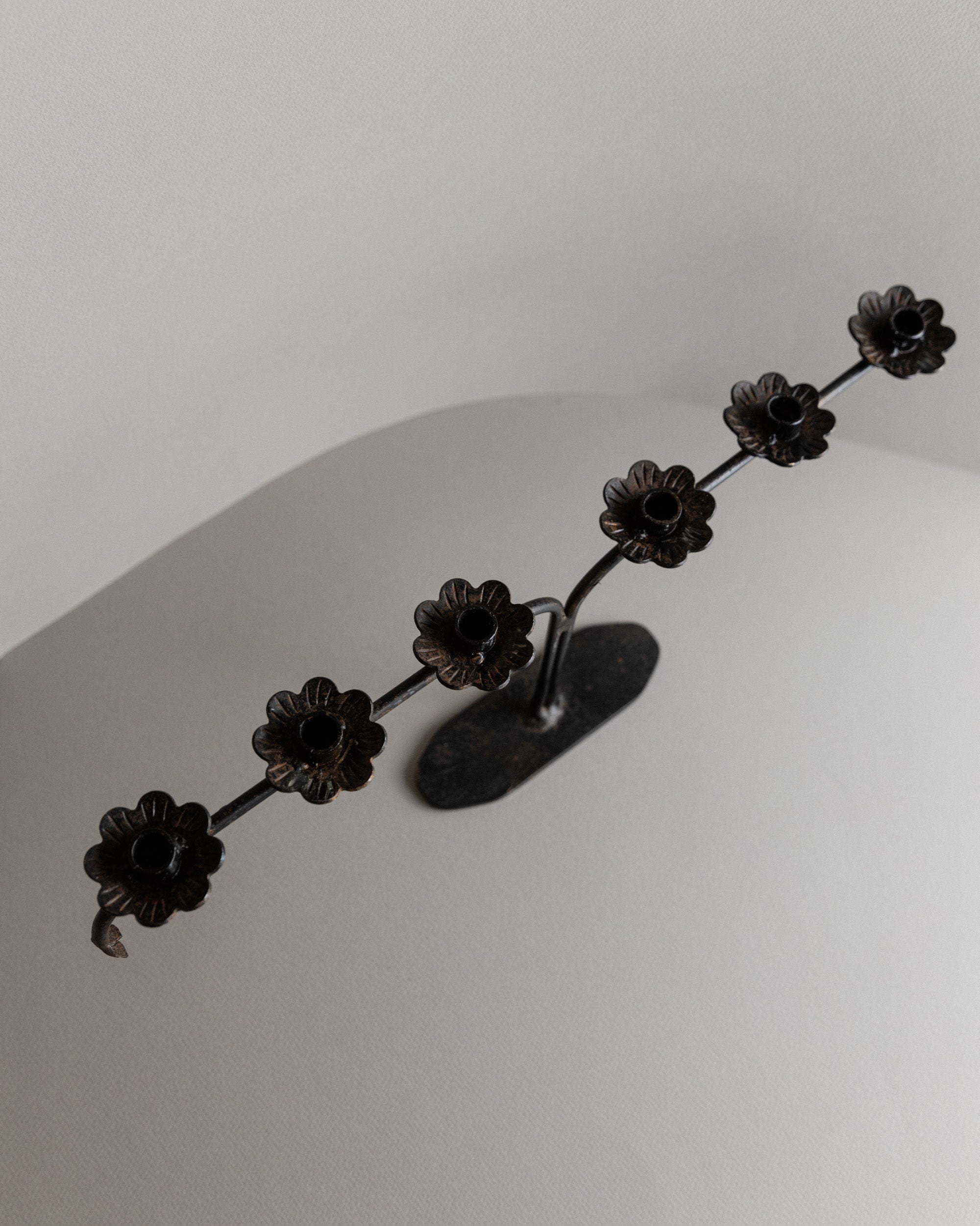 This vintage Bottega Jacobs Iron Candleholder from Italy (1960s) features flower-shaped elements on a curved rod, mounted on a base, set against a neutral background. Perfect for table decoration, it exudes brutalist design charm.