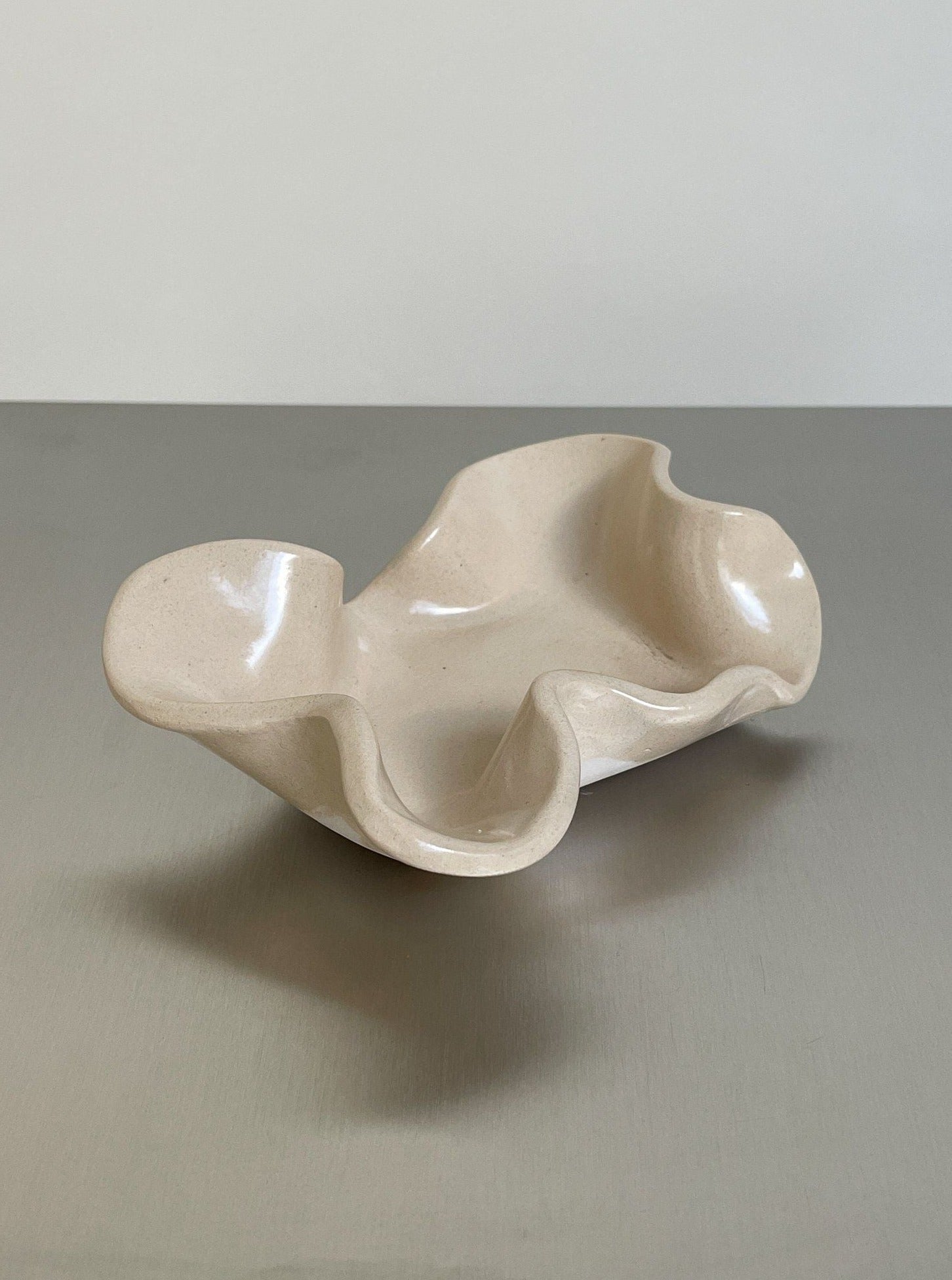 The 2222Studio Soapholder in stoneware features a beige, wavy-edged, handmade ceramic design with an abstract organic shape—an elegant accent for any bathroom decor.