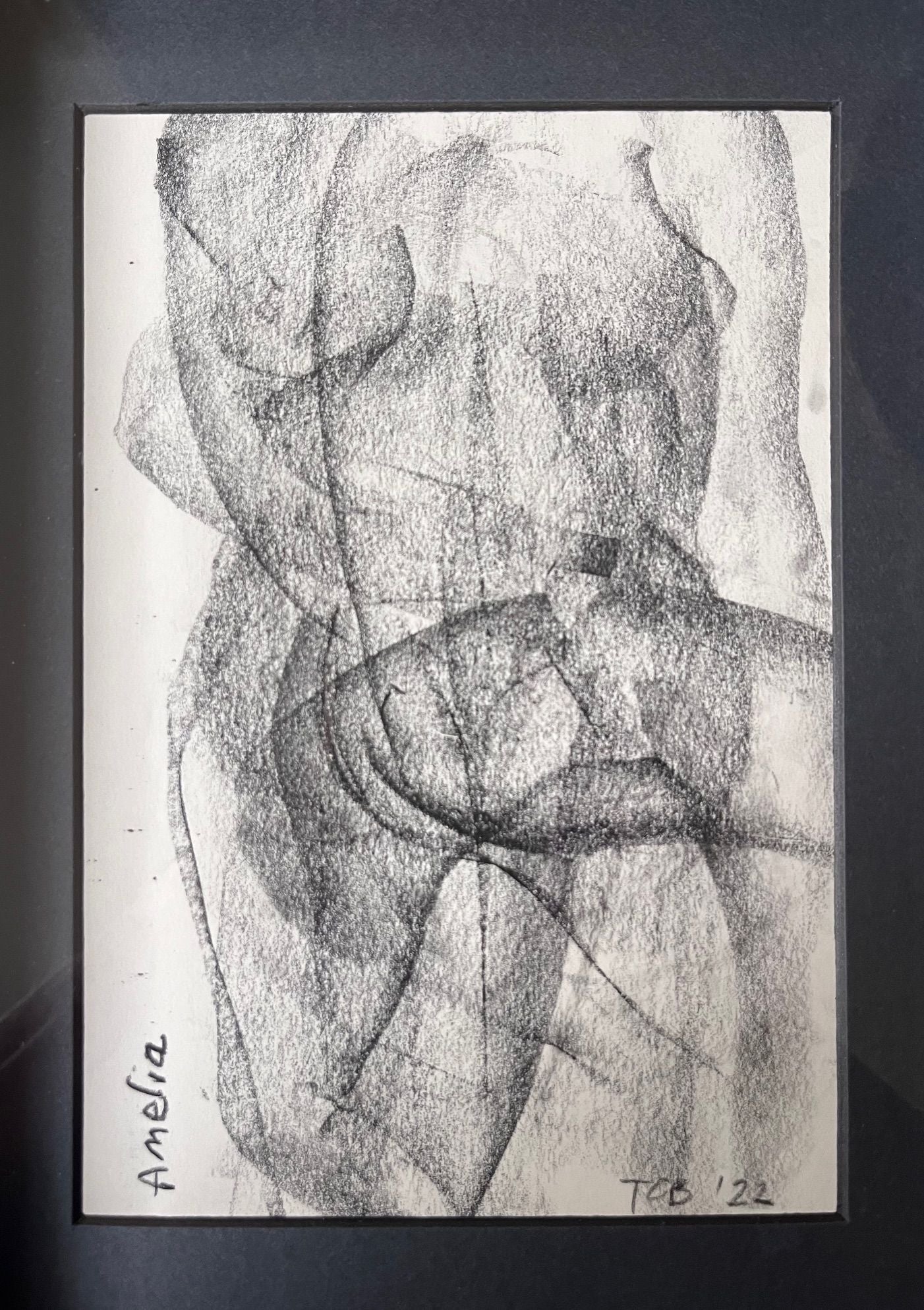 A grayscale abstract charcoal drawing from Médecine titled Croquis Drawing no.VII "Amelia" depicts overlapping, loosely sketched forms of a human body. The lines and shading create a textured, layered effect. The artist's signatures, "Amelia" and "TE '22," are visible in the corners of this framed piece by a contemporary English artist.