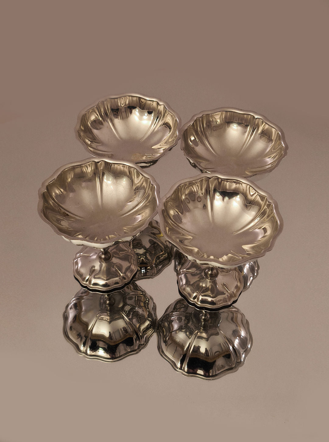 A set of 4 cups by Les Objoies, featuring elegant, fluted metallic designs and scalloped edges, is beautifully displayed on a glossy surface in a diamond pattern against a neutral background.