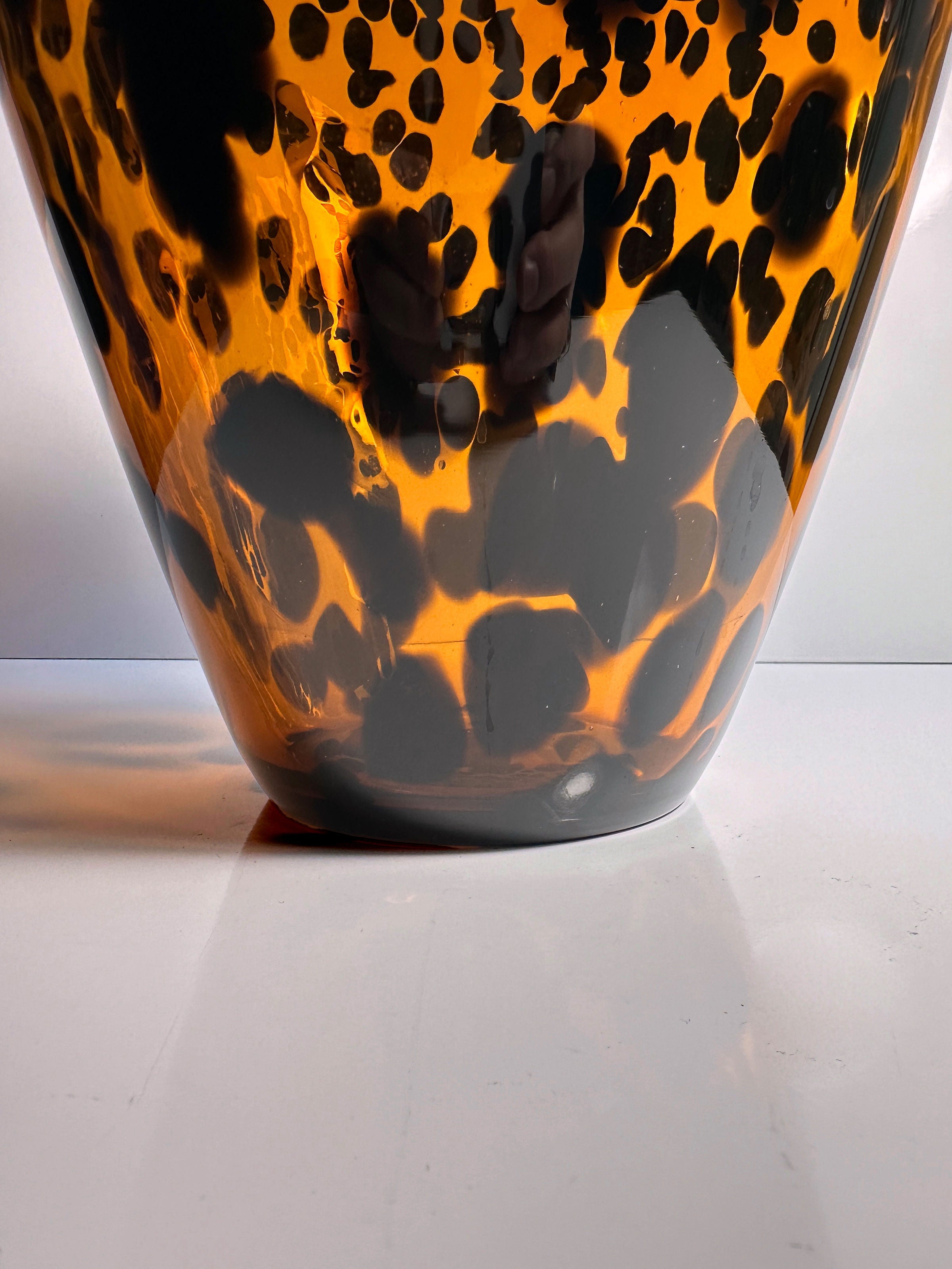 Close-up of the Tortoise vase Murano for Christian Dior - 1960s by Dodo Vintage, featuring an abstract leopard print design in shades of black and orange. The shiny surface reflects light, adding depth and texture against a plain white background.