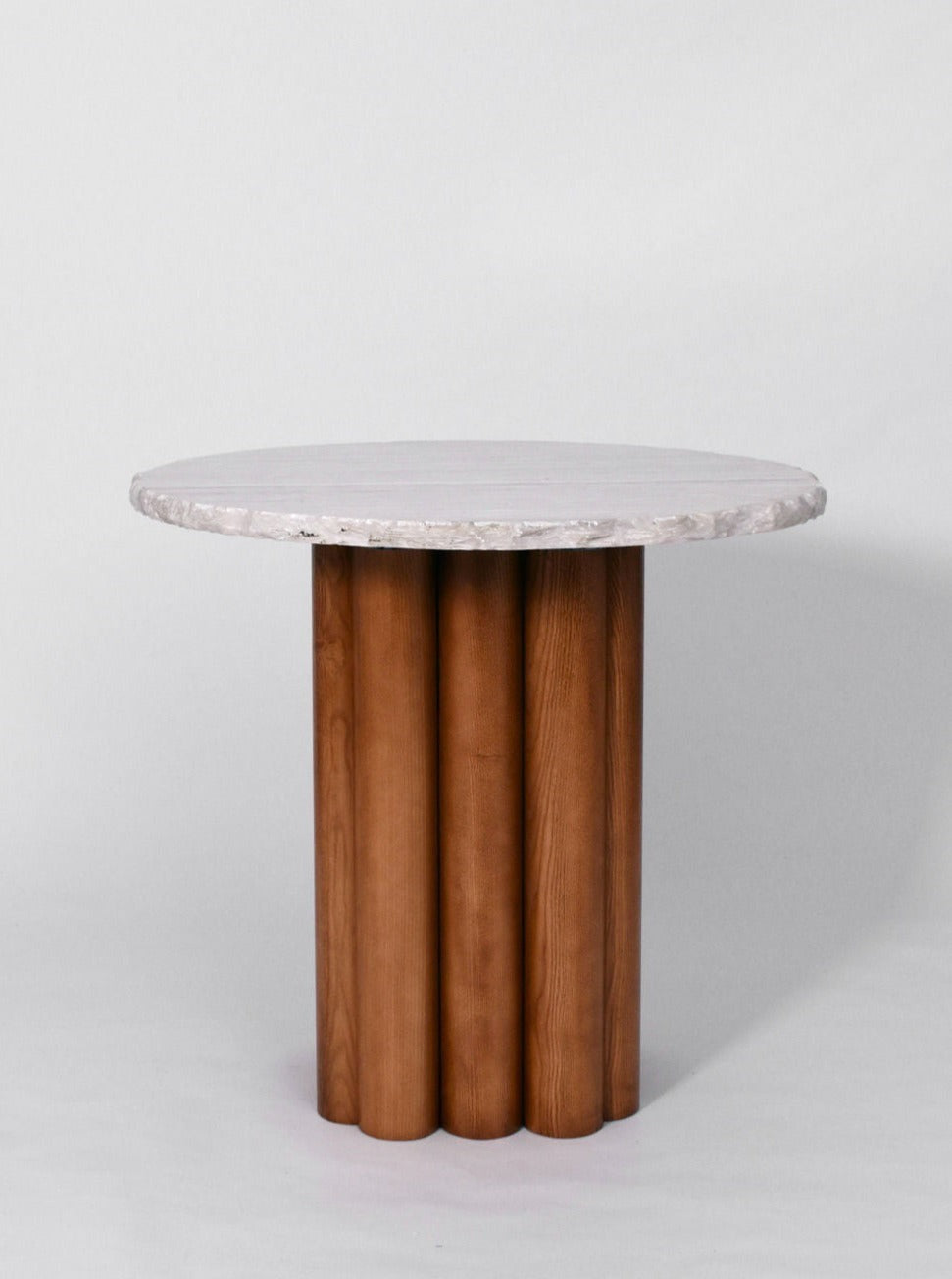 A minimalist "Carrasqueira" table, Barracuda edition boasting a textured white stone top and a wooden round base composed of four oak columns. The design is simple and elegant, with natural materials providing a rustic yet modern look. It stands against a neutral gray background, by Barracuda Interiors.