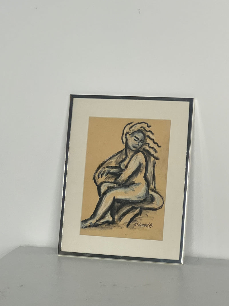 Porter Studio presents "Pastel Drawing" by E.D Connor: a stylized seated figure with flowing hair on beige, set against gray. Framed in thin polished chrome, the artwork is complemented by a white mat.