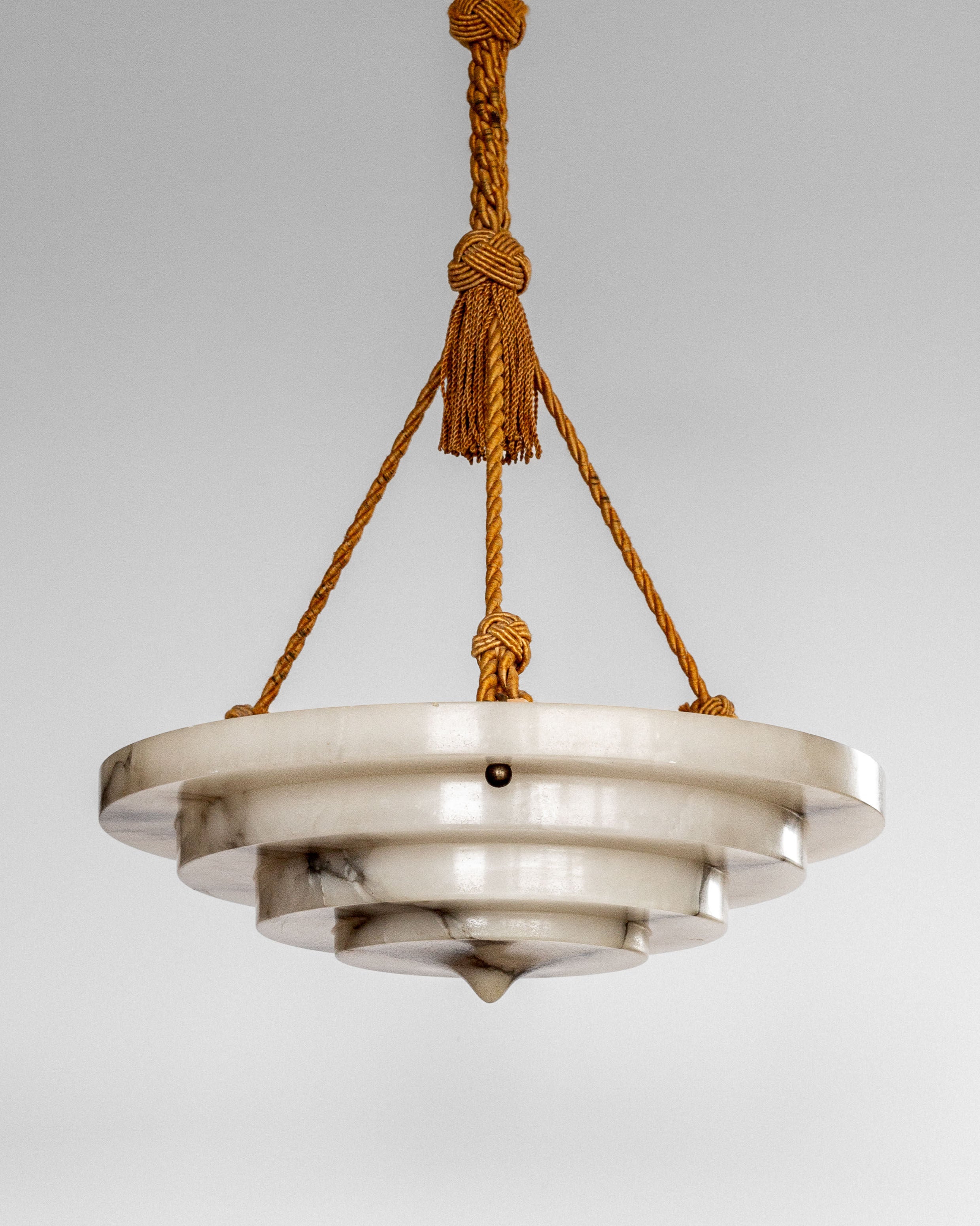 Spigel's Art Deco Alabaster Pendant Chandelier features three circular tiers of alabaster suspended by braided gold-colored cords, embodying Swedish Grace. The cords converge elegantly at the top against a plain light gray background.