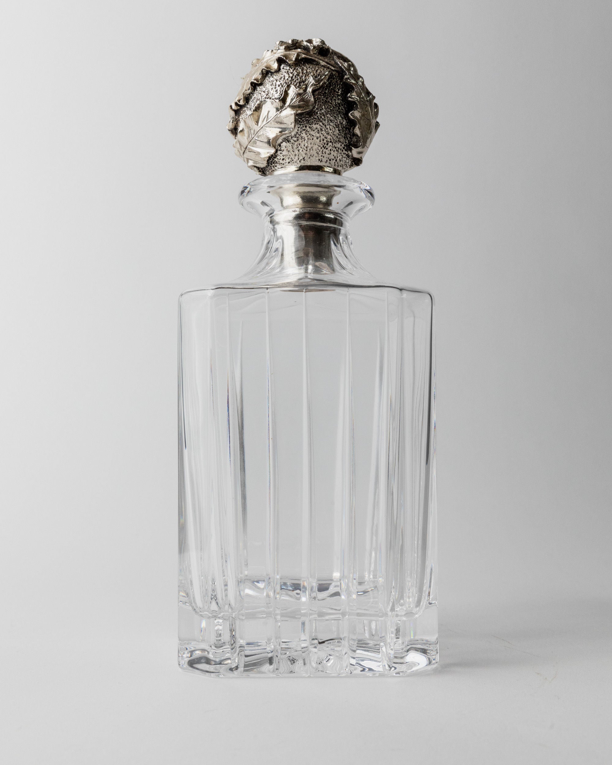 Detailed view of ornate silver stopper on crystal glass decanter