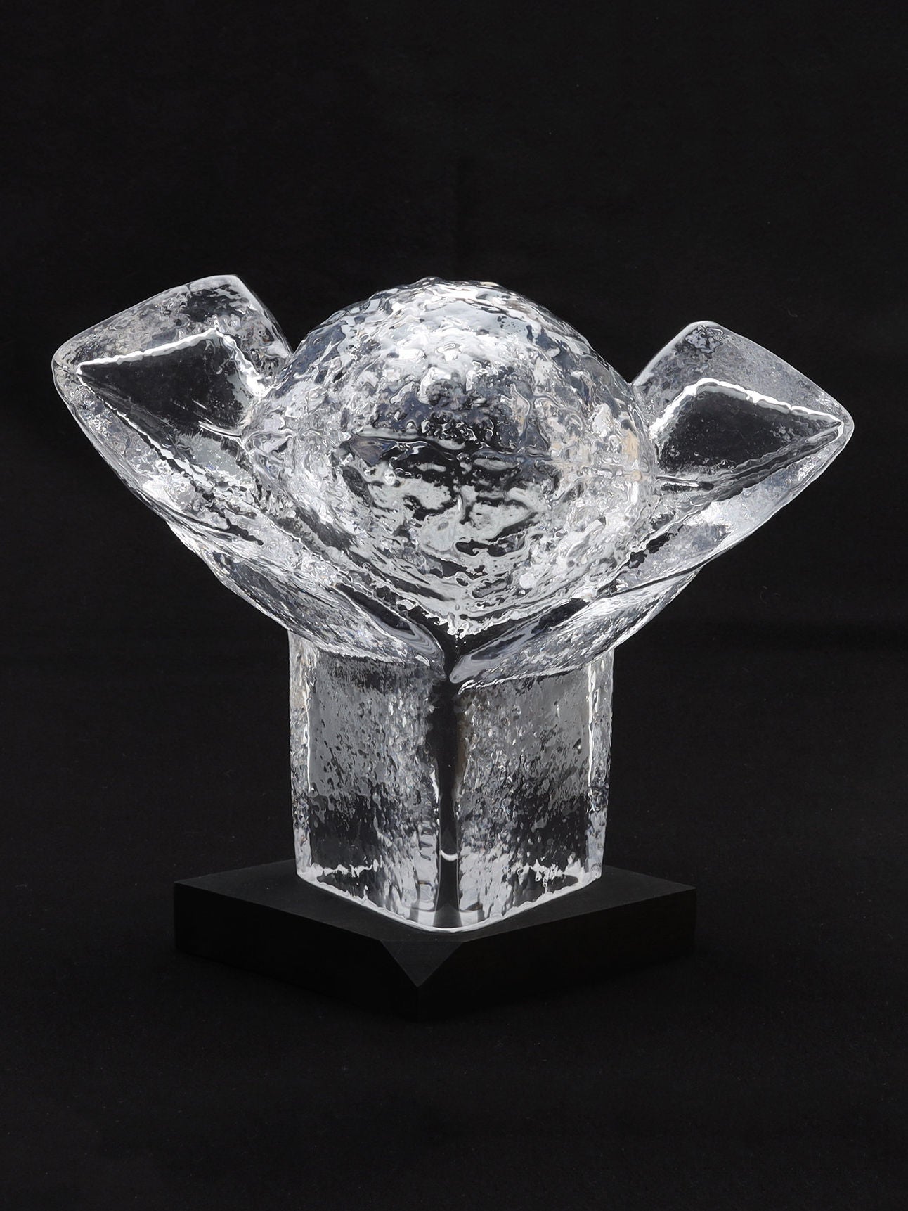 The Very Large Abstract Glass Sculpture by RELIC LONDON, evocative of a clear crystal trophy, features a rough-textured spherical top and two angular arms extending upward from a sturdy square black base. The solid black background accentuates its intricate design, making it a coveted piece for any discerning art collector.