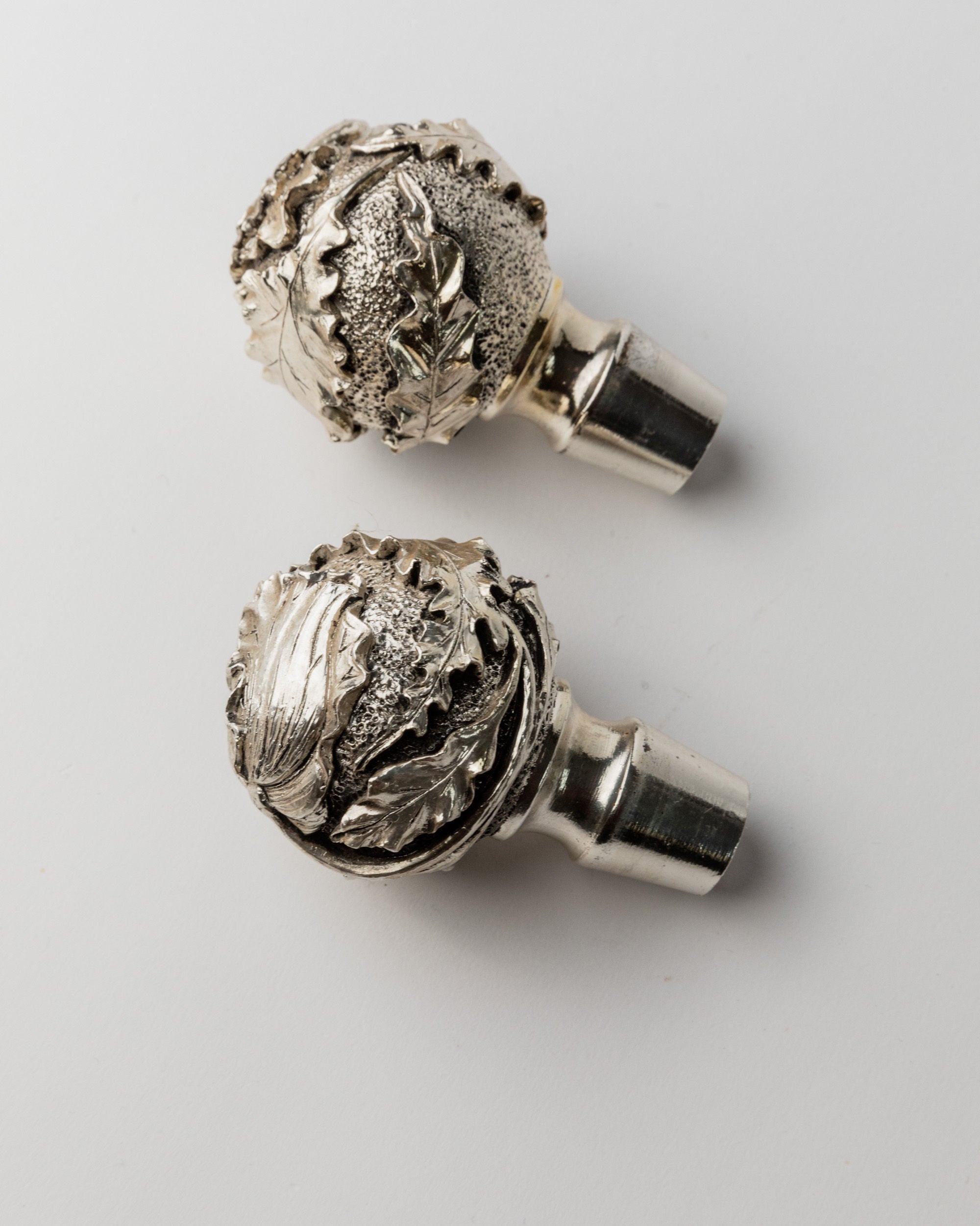 Close-up detail of ornate silver decanter stoppers with leaf motifs
