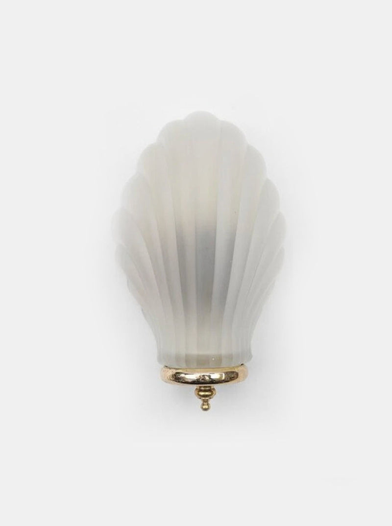 The Shell Wall Light by Les Objoies features a frosted glass seashell-shaped knob with a gold base, evoking 1960s Italian elegance, and is displayed against a plain white background.