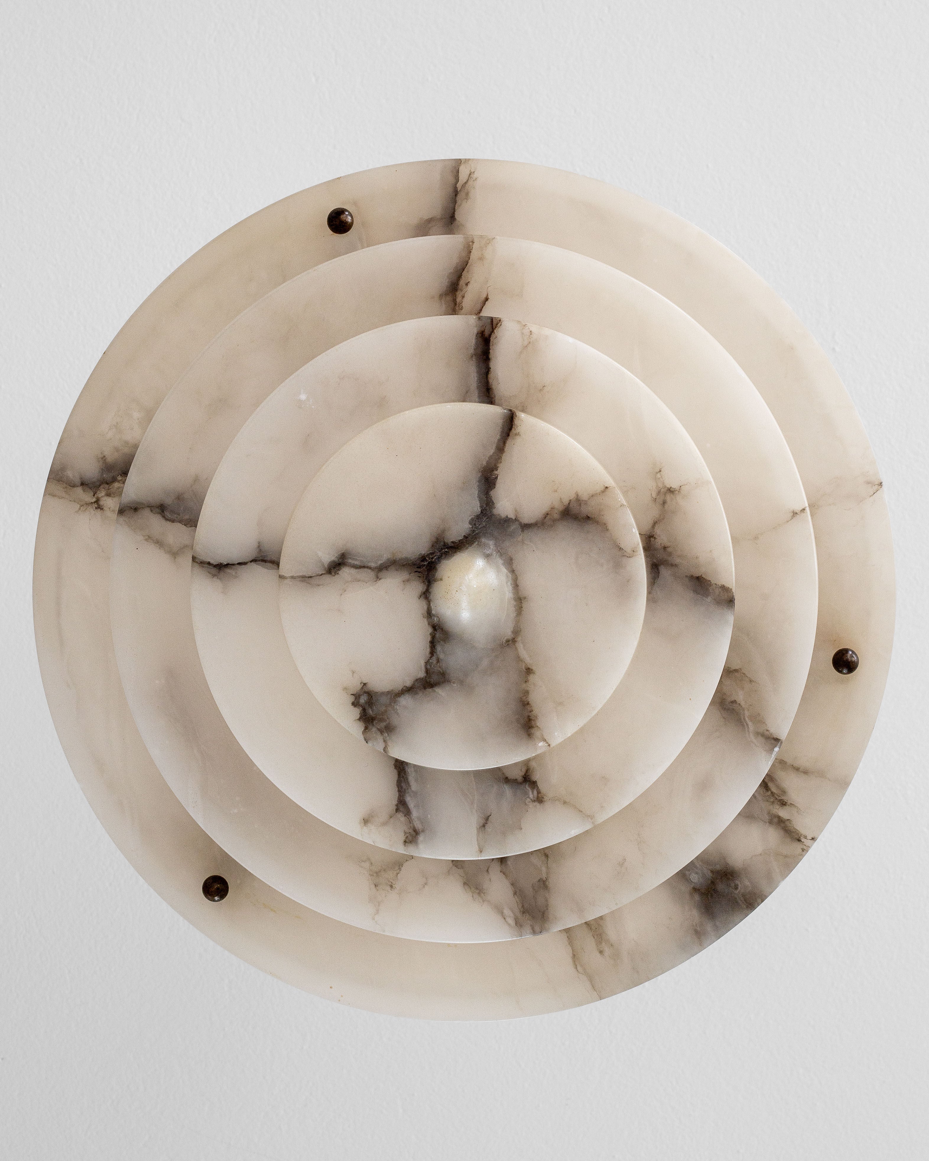 The Spigel Art Deco Alabaster Pendant Chandelier showcases concentric circular layers with natural veining patterns and three metal accents encircling a central bulb, providing decorative and functional period lighting against a white background.