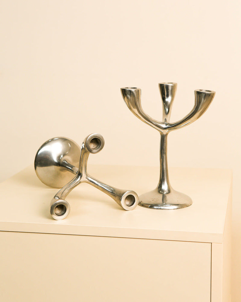 Vintage Italian chrome candleholders on cream surface detail view