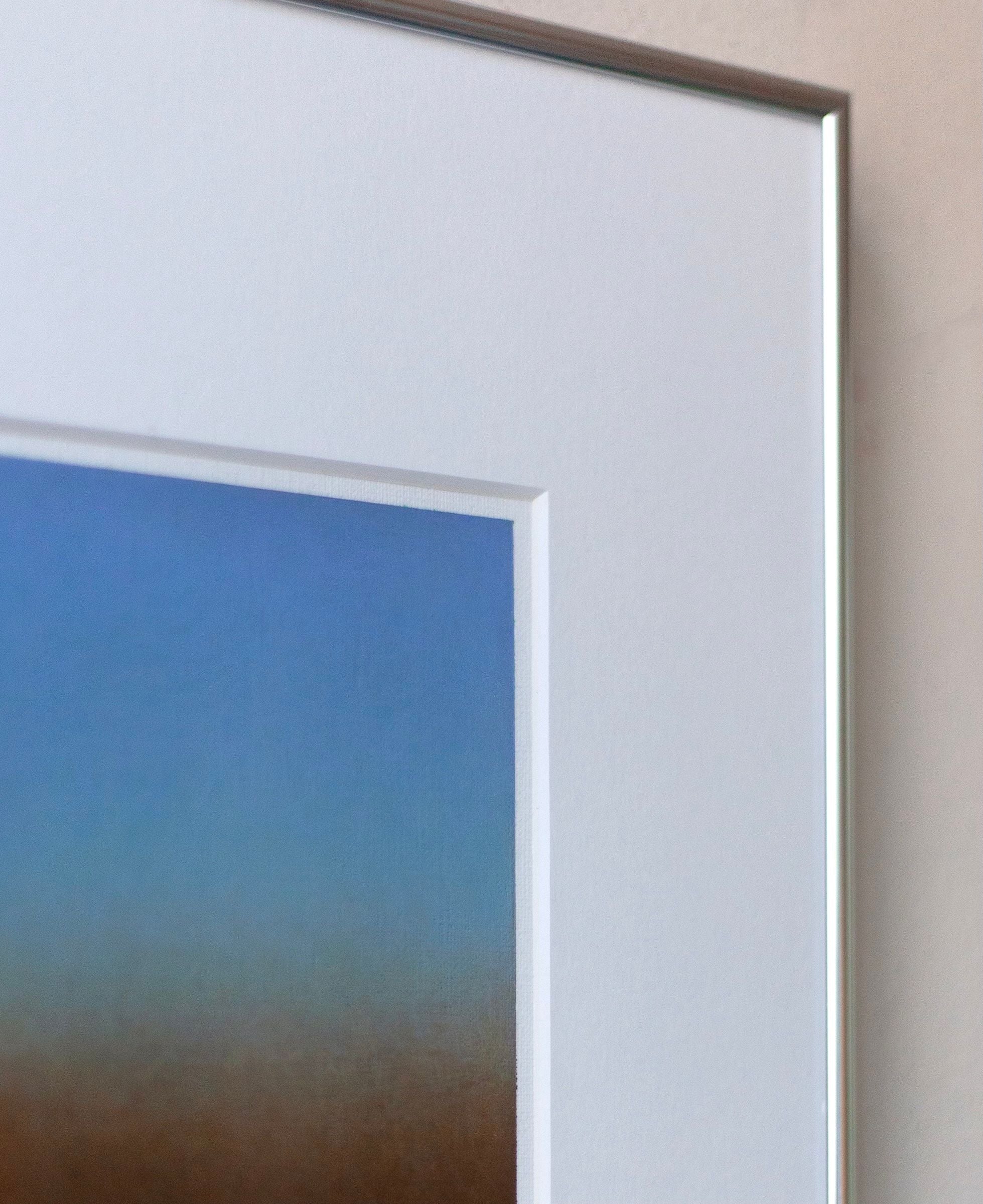 Close-up of Rebecca von Matérn's 'Untitled' Painting, 2024, showcasing a blue-to-brown gradient. This signed artwork is set on a white mat and partially visible inside an elegant aluminum frame against a plain background.