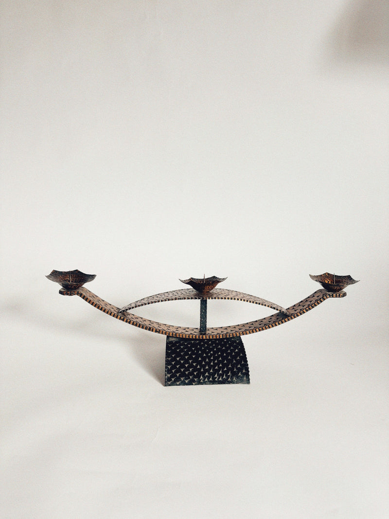 The Huerto Two Tone Metal Candleholders feature three flower-shaped holders on curved arms and a textured base, offering vintage charm in decorative black metal, beautifully set against a plain white background.