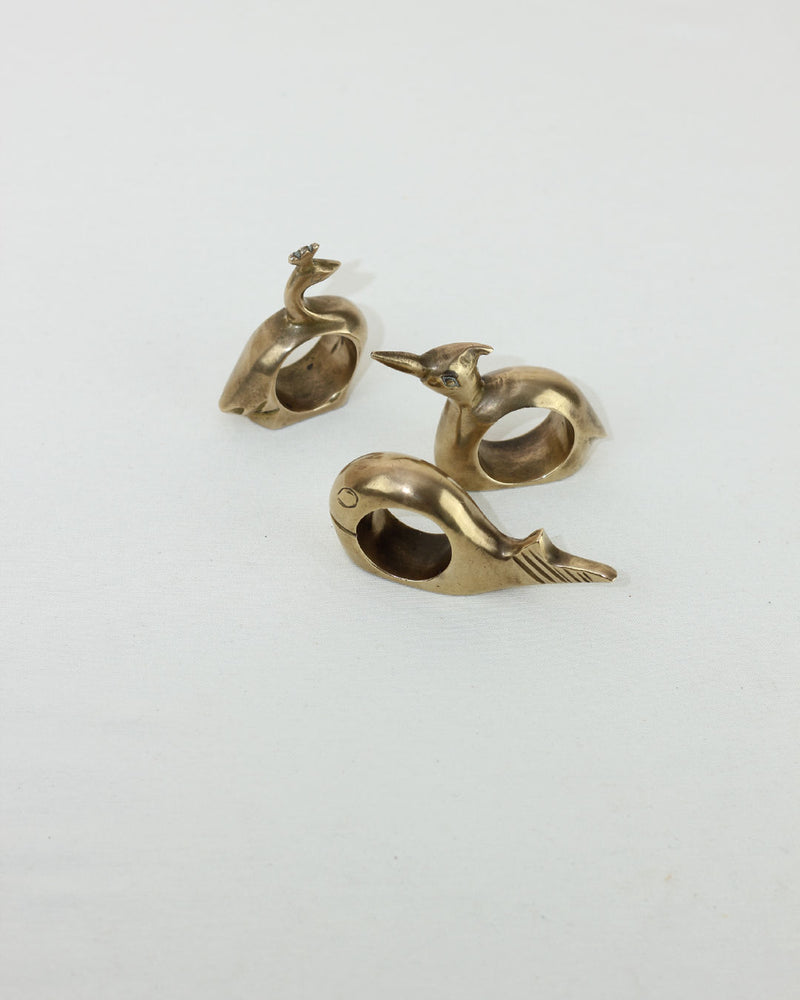 Three brass animal-shaped napkin rings with sculptural curves