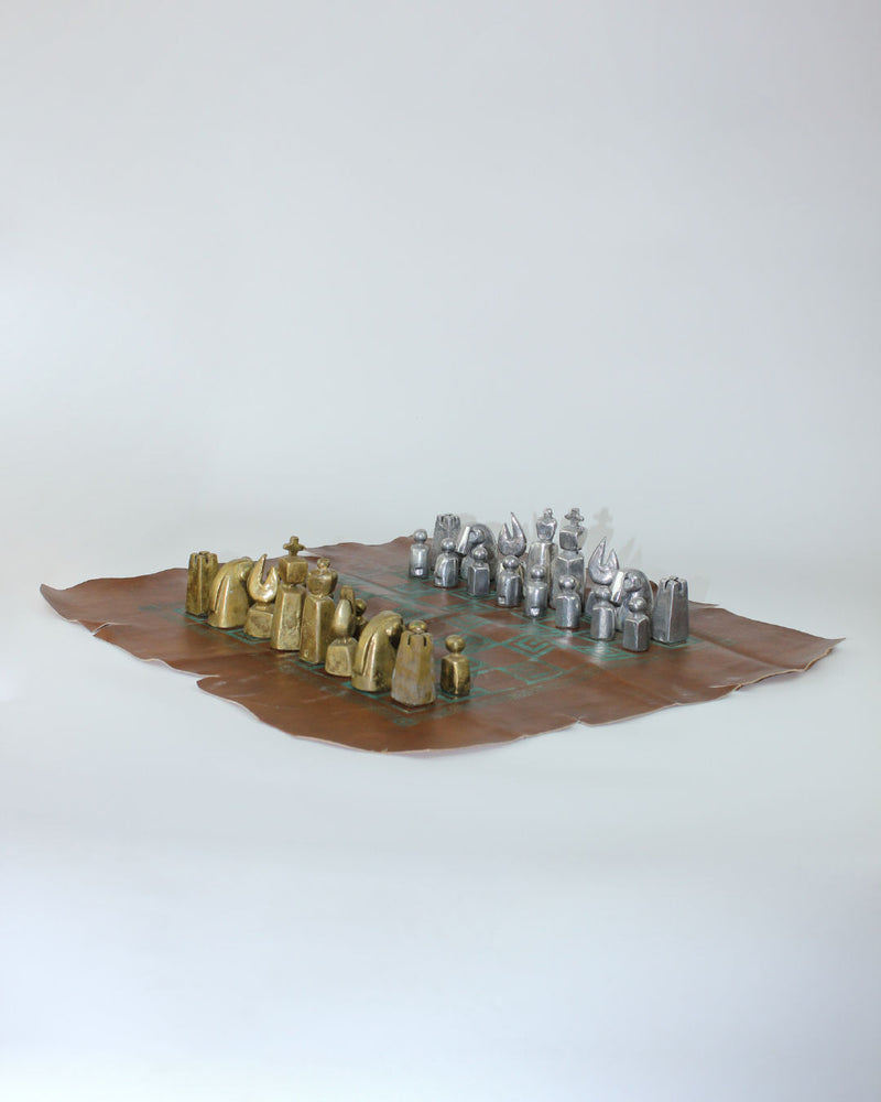 Brutalist chess set with gold and silver pieces on leather board 1970s