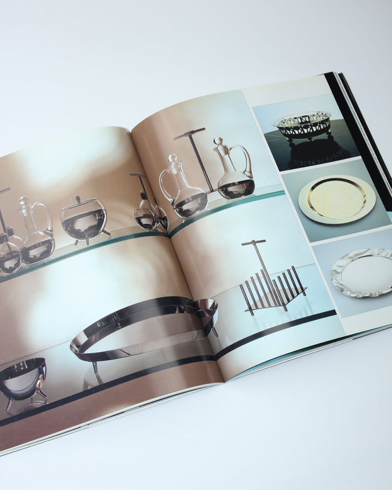 Open Alessi design book showing glassware and serving pieces catalog pages