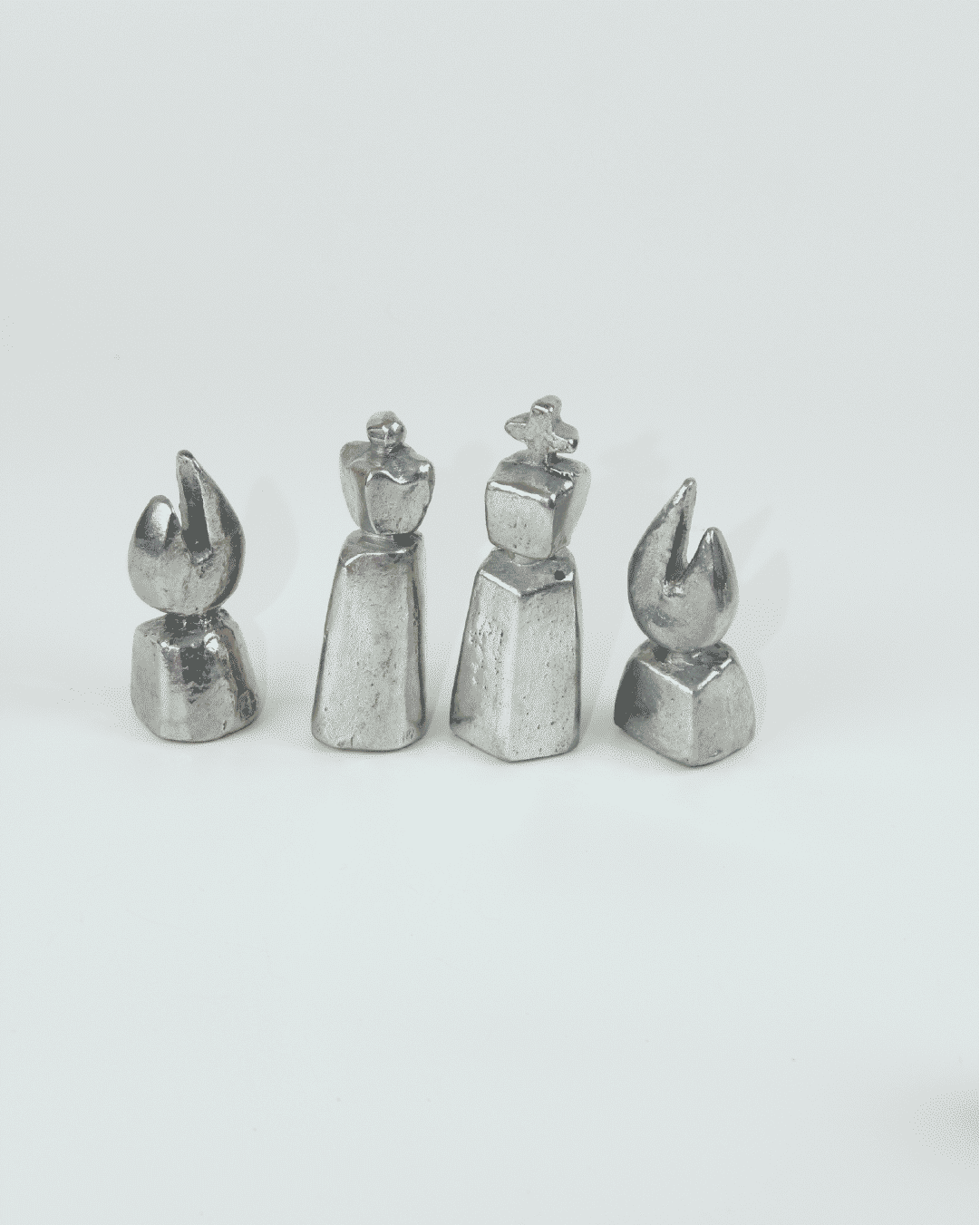 Four metallic brutalist chess pieces showing king queen and bishops from 1970s set