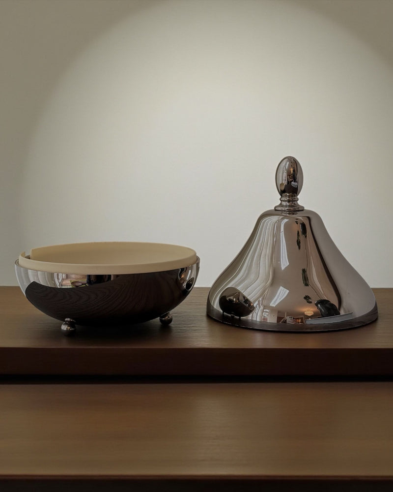 Pear-shaped chrome serving dome with matching bowl on wooden shelf