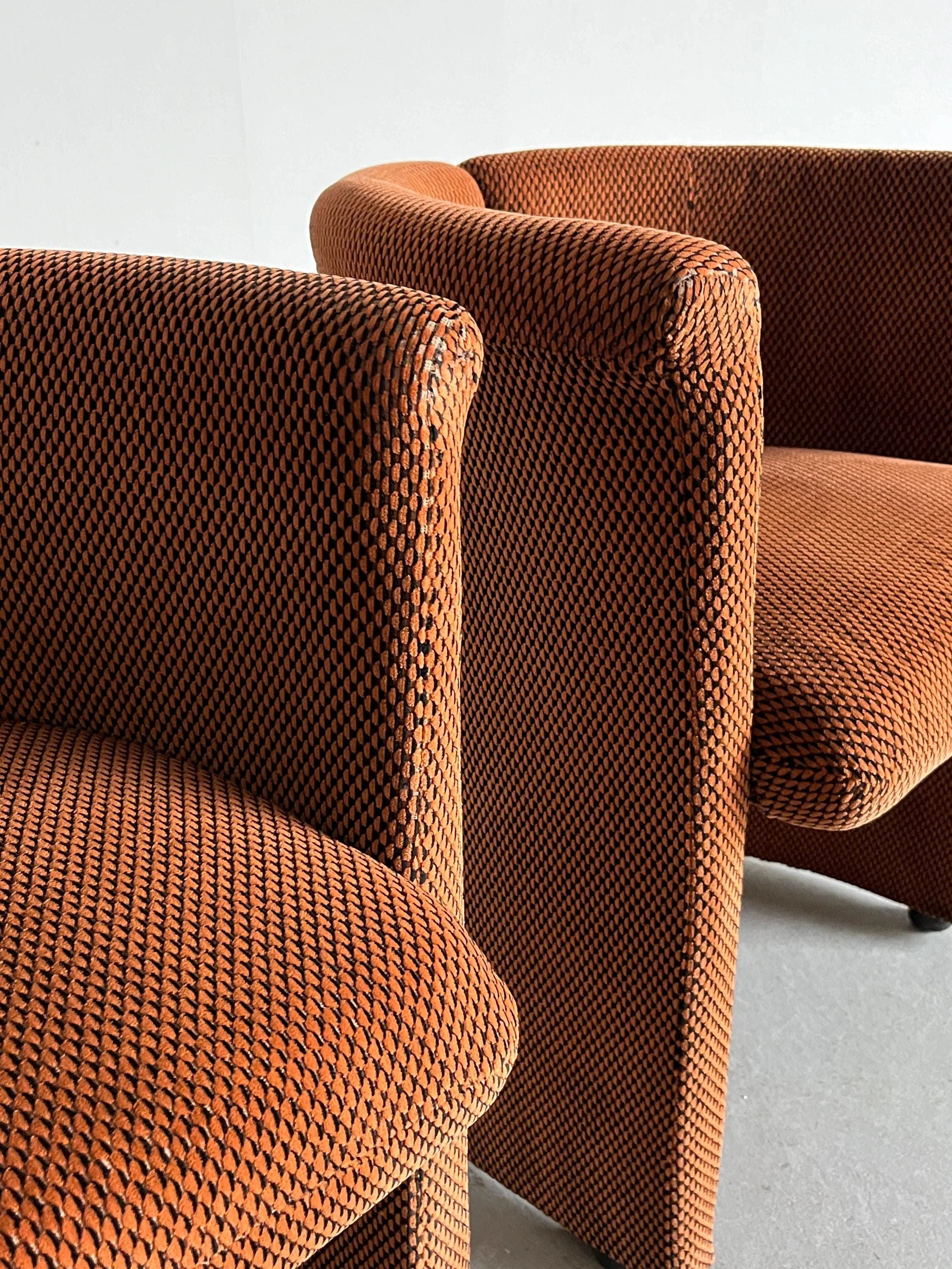 This pair of Postmodern Armchairs by Cherry Cargo features closely arranged, comfortable, brown upholstered chairs with rounded backs and a textured checkered fabric, set against a plain light-colored background.