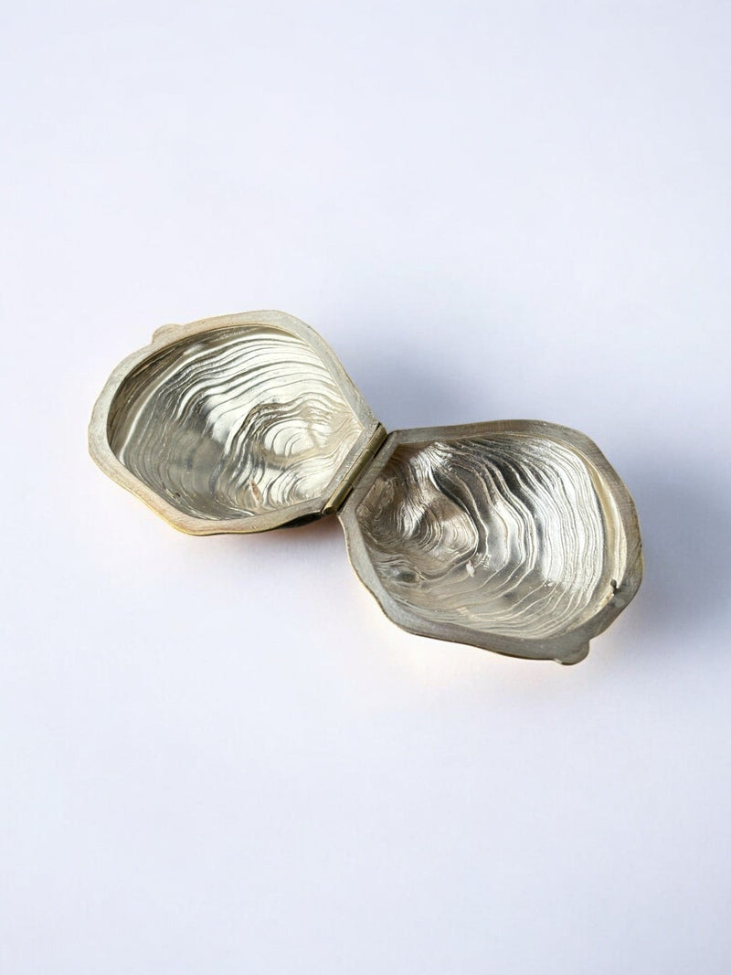 Golden brass oyster shell pill box interior detail showing concentric ridged chambers