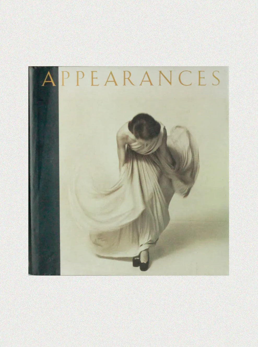 Book cover titled "Appearances" featuring a sepia-toned image of a person gracefully bending forward while wearing a flowing, draped dress. This stunning libro de fotografía de moda by Boga Avante Shop showcases the work of fotógrafos famosos and will be exhibited at the renowned Victoria & Albert Museum.