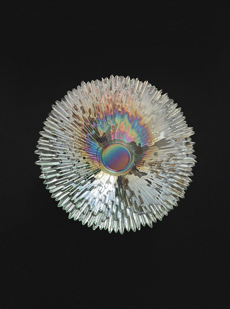 The Tapio Wirkkala "Revoltunet" Art Glass Bowl by Vintage Stories, with textured iridescent glass and sunburst-like spikes, is showcased against a solid black background.