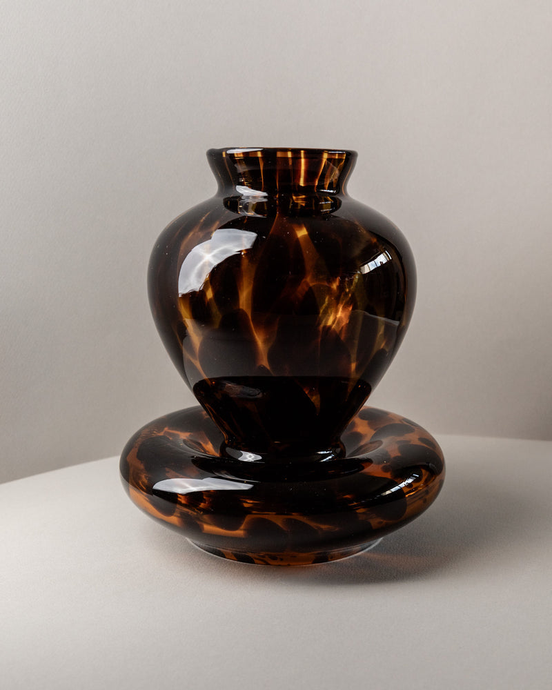 A glossy, dark brown Set of Murano Glass Vase and Bowl - Tortoise by Bottega Jacobs (Italy, 80s) featuring an abstract tortoise shell pattern sits on a light surface with a pale background—true Italian glass artistry.
