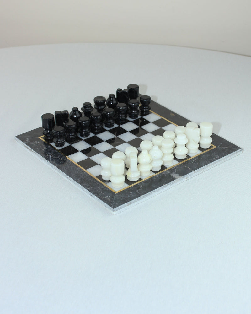 Black and white marble chess set with cylindrical pieces on checkered board