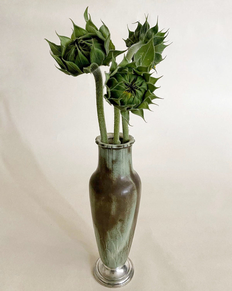 Vintage green ceramic vase with dried sunflower stems on metal base