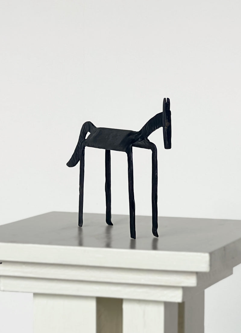 Black iron horse sculpture with elongated legs on modern display pedestal