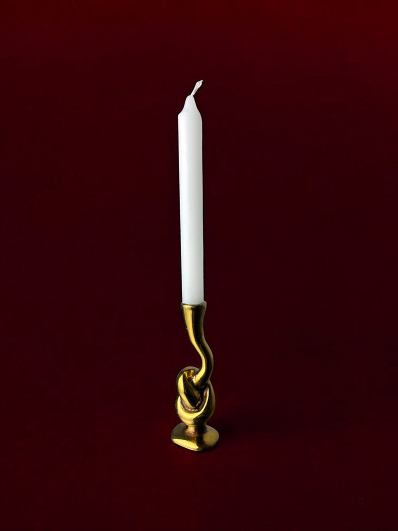 Bronze knot candleholder with twisted sculptural base holding white candle