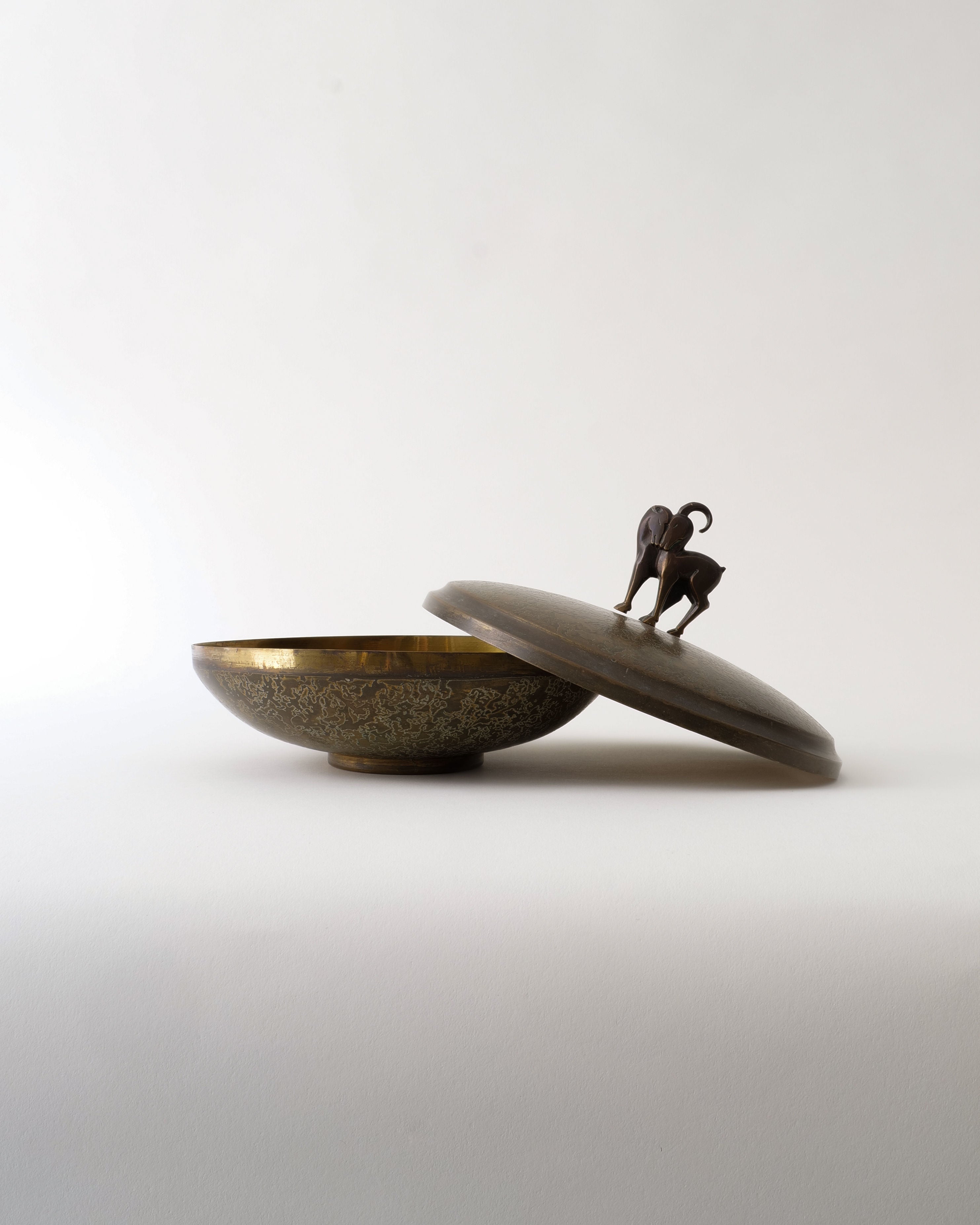 The Deco Box by Pierre Amédée Plasait from Collection apart is a decorative Art Deco brass box with an ornate lid, slightly open, topped with a small animal figurine as the handle. Set against a plain white background.