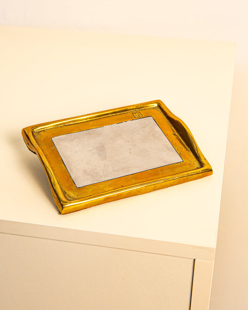 The Treaptyque Vide-poches by David Marshall 80's features a rectangular brass-and-silver design with a flat gray center and raised edges, displayed on a light table against a plain background, reflecting ‘80s style.