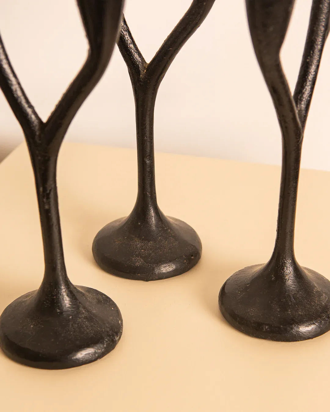 Close-up of the Treaptyque’s ‘Arbre’ set, featuring three 80's black cast aluminium candleholders with slender stems and round bases. They stand elegantly on a light surface, highlighting Italian craftsmanship against a simple backdrop.