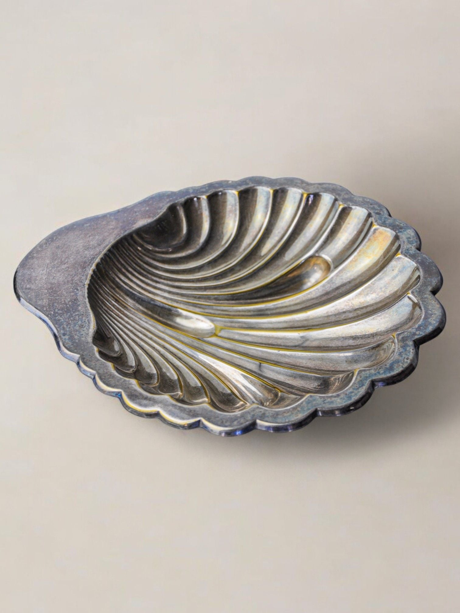 The Large Shell Shaped Vide-Poche by Malamar Studio, Italy, 1970, is a scallop-shaped silver-plated dish with ribbed texture and weathered finish. Its curved edges and radiating lines on a neutral background reflect a vintage Italian design.