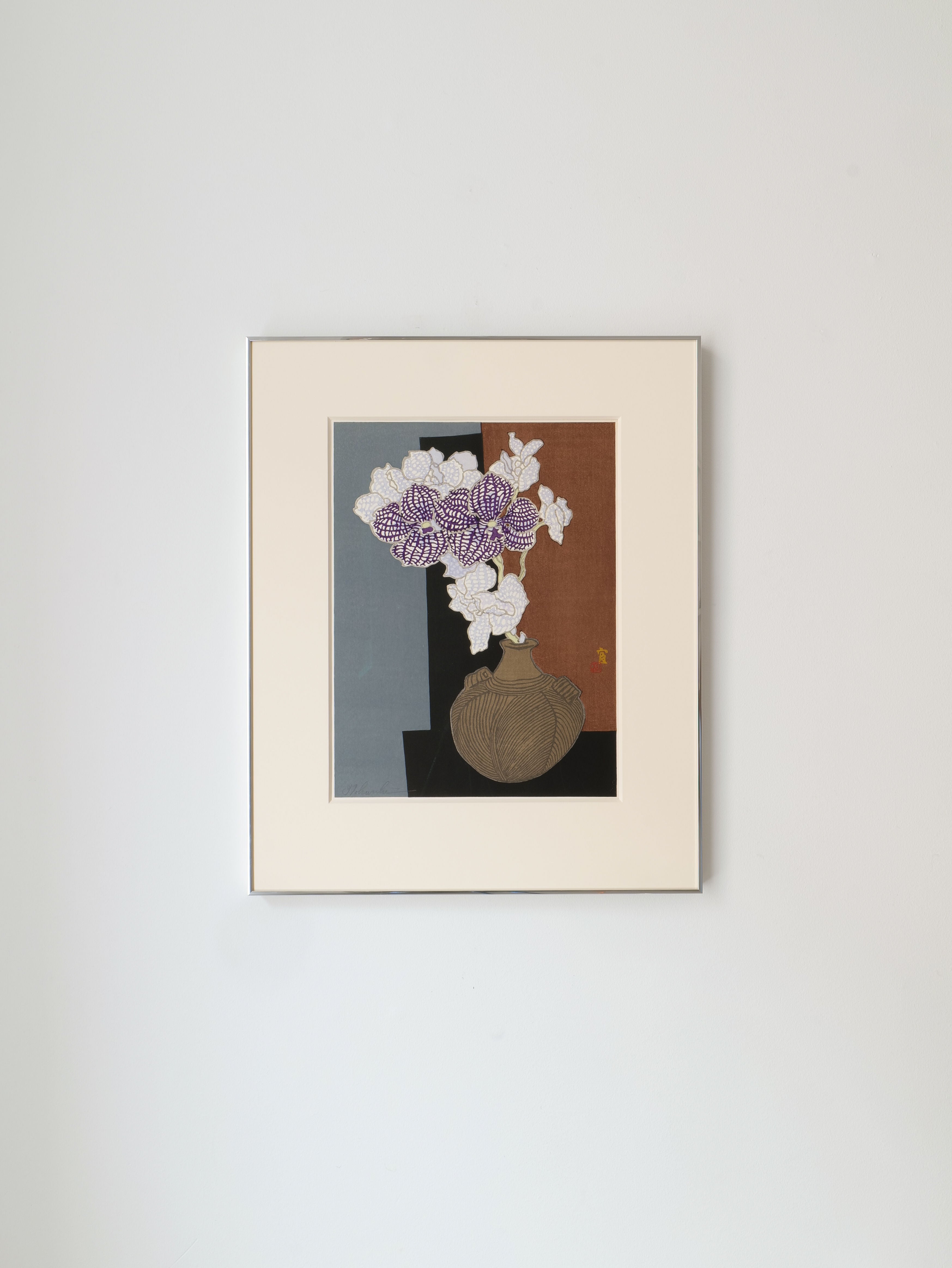 An off-white framed artwork resembling Tokuriki Tomikichiro's Japanese woodcut print from the 1980s showcases a vase with white and light purple flowers on a muted gray-brown background, evoking the delicate beauty of an orchid. It is part of Collection apart.