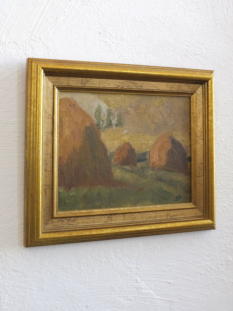 Framed 1950s landscape painting depicting golden haystacks in field