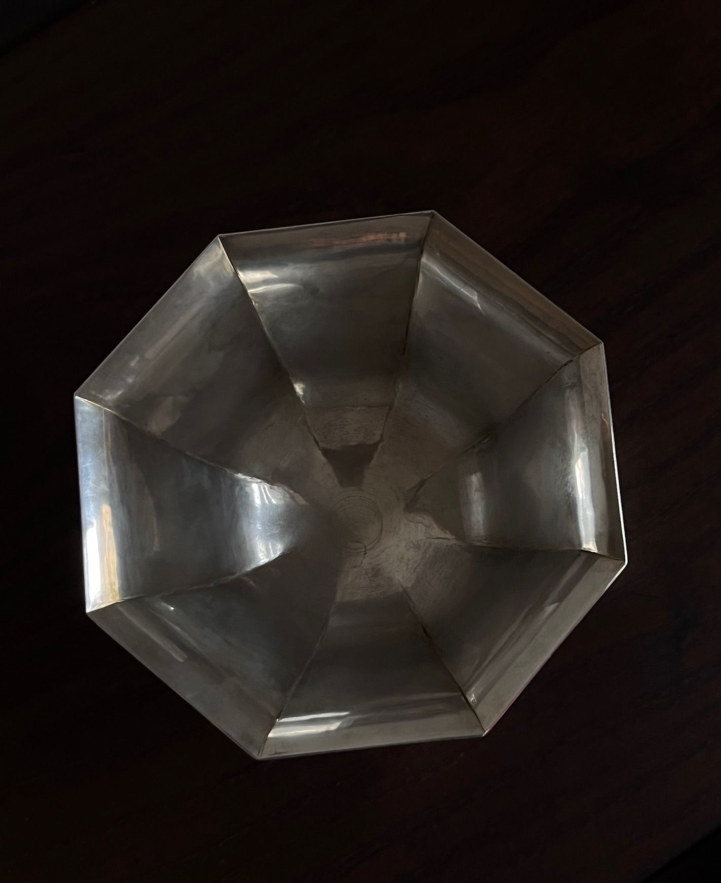 The Art Deco Silver Bowl 1949 by Médecine, viewed from above, showcases its metallic octagonal design with a polished surface reflecting light, embodying modernist elegance against a dark background.