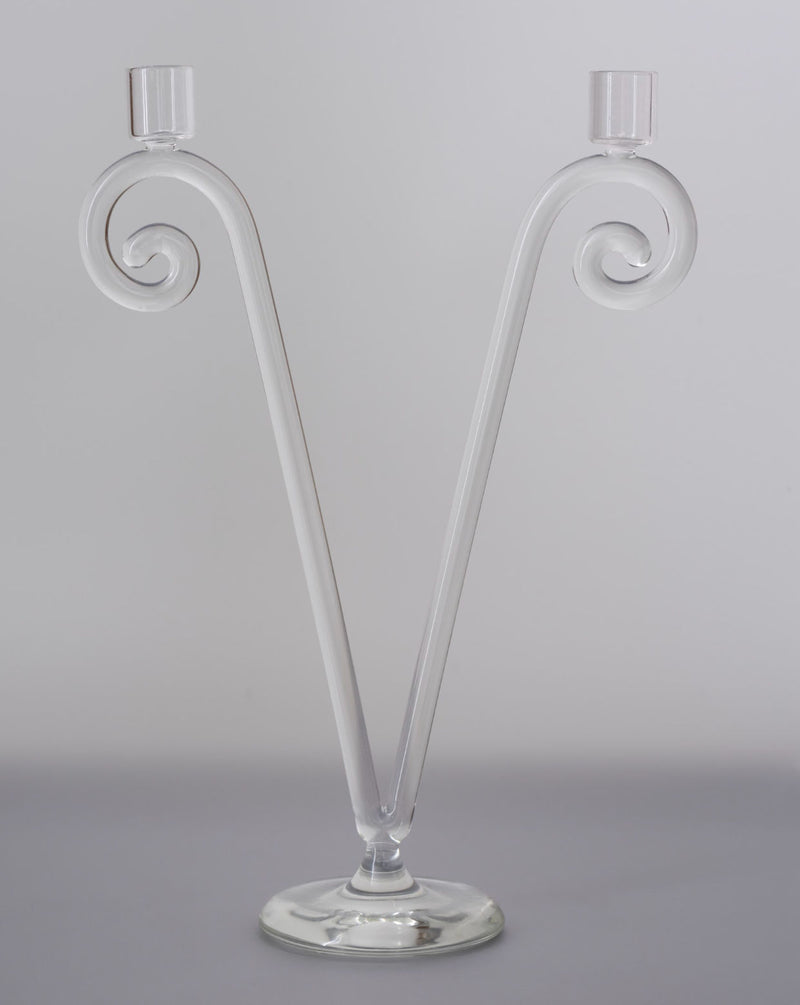 The Double Stem Spiral Candleholder by Sophie Lou Jacobsen features two clear glass arms curving in a V-shape with candle cups on a round base—an elegant accent for classic dining or decorative art lovers.