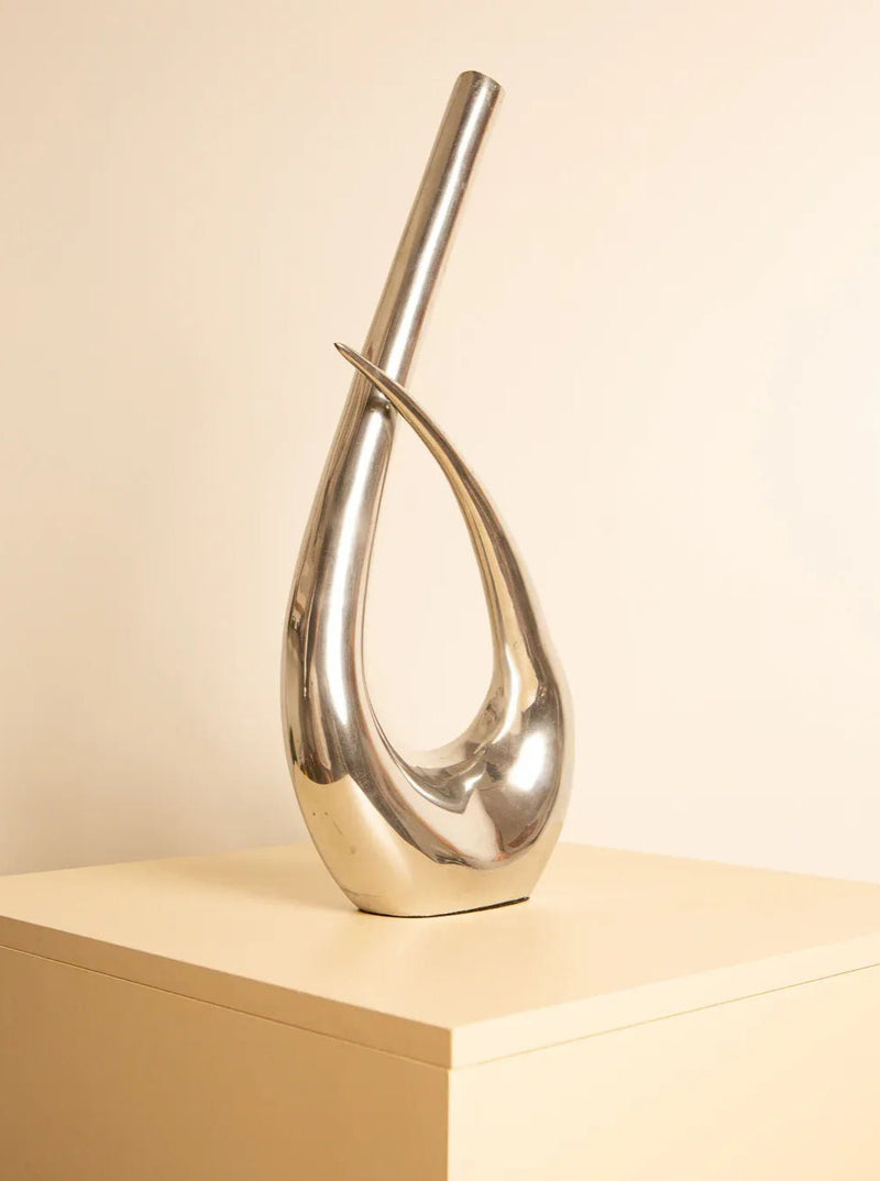 Close-up of the intricate Clef design on the metal vase, reflecting the light and shadows