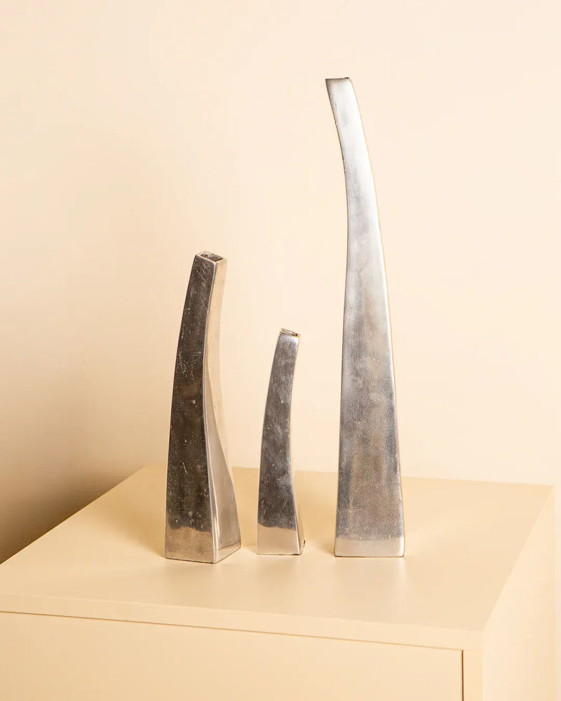 The Treaptyque Set of 3 Italian Vases in Cast Aluminum 80's features abstract silver designs of varying heights on a light surface, set against a neutral background to exude timeless elegance with their sleek, curved shapes.